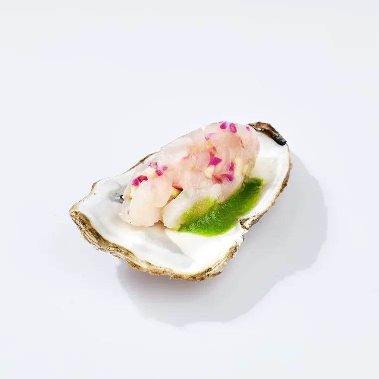 Huître garnie d'une préparation de la mer et d'un trait d'huile verte