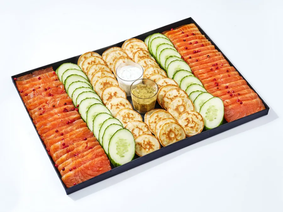 Plateau noir de blinis, rondelles de concombre et saumon, avec deux sauces