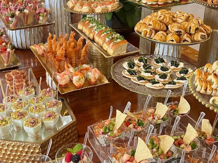 Buffet de réception sur présentoirs dorés, entouré d'orchidées blanches