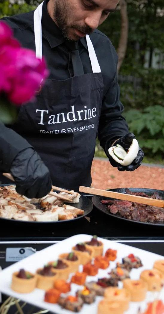 Cuisinier en tablier Tandrine en service, devant un plateau de pièces cocktail
