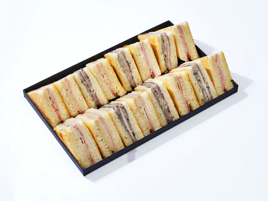 Plateau noir de sandwichs de pain de mie garnis, coupés en triangles