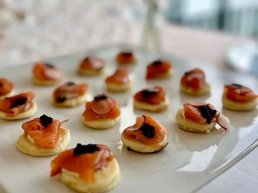 Blinis garnis de saumon et d'œufs de poisson, sur plateau clair