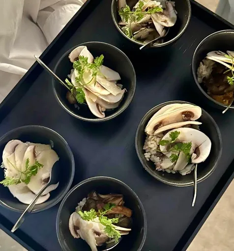 Bols individuels de salade de champignons émincés et herbes fraîches, sur plateau noir